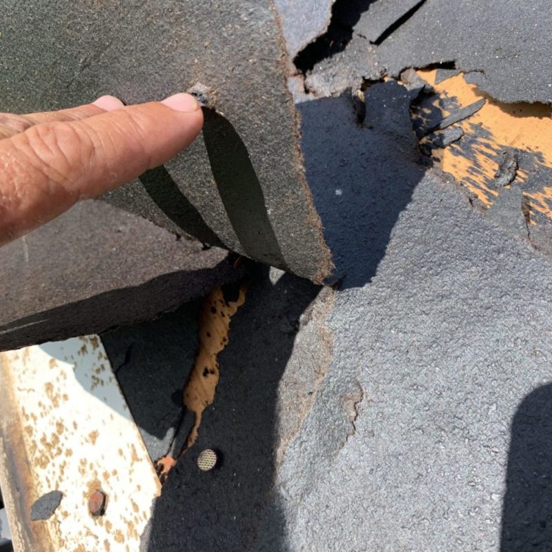 closeup of damaged shingles being pulled up