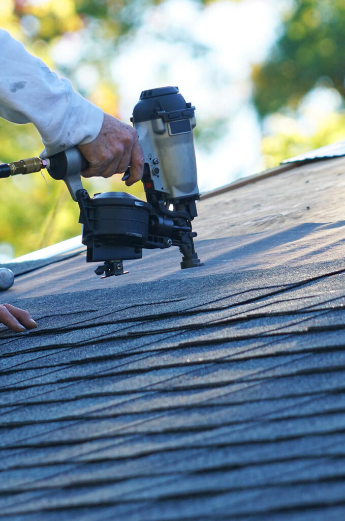 closeup of nail gun being used on a roof - Roofing Louisiana Roof Replacement